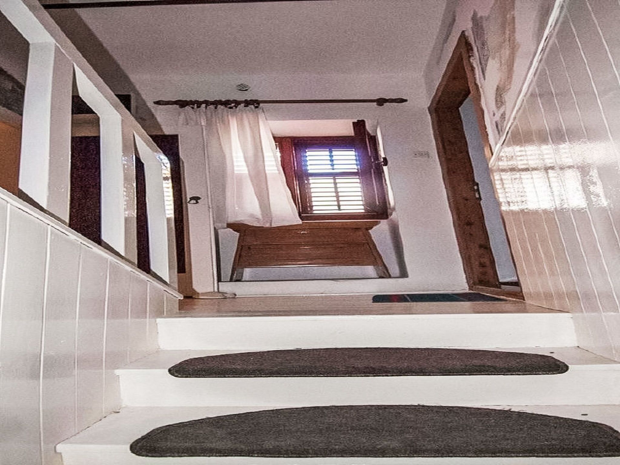 A staircase leading to a room with a window, a door, and a curtain.