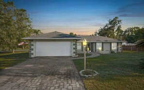 A single-story house with a garage, a well-maintained lawn, and a street lamp. - Golden Key Vacation Home/ Pool & Game (Spring Hill)
