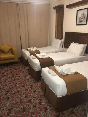 A hotel room with two beds, a sofa, and a patterned carpet. - Sky View Hotel (Madinah)