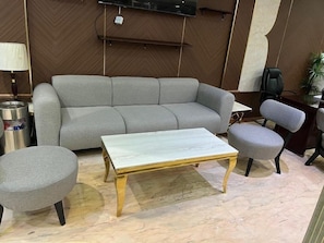 A modern living room with a grey sofa, a marble coffee table, and matching armchairs. - Sky View Hotel (Madinah)