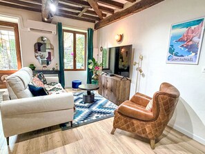 A living room with a sofa, armchair, TV, and a poster on the wall. - Hypercentre Dijon by Interhome (Dijon)
