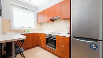 Une cuisine moderne avec des meubles en bois, un réfrigérateur en acier inoxydable et un four encastré.