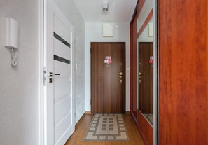 Un pasillo con puerta de madera, pared blanca con teléfono y alfombra estampada.