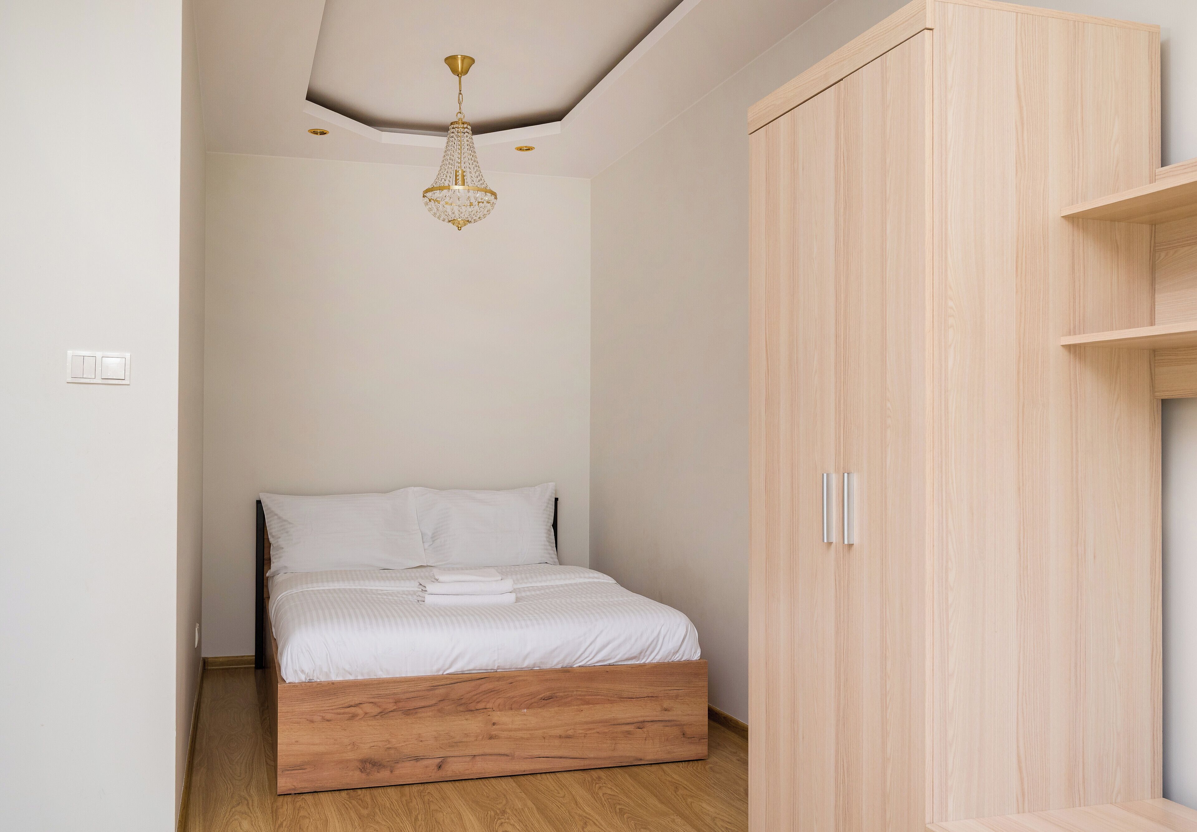 Ein Schlafzimmer mit einem Holzbett, einem Kleiderschrank und einer Chandelier.