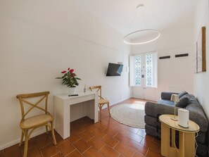 A modern living room with a white desk, two wooden chairs, a grey sofa, a round rug, and a flat-screen TV mounted on the wall. - Contemporary House by Interhome (Viareggio)