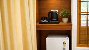 A compact kitchenette with a coffee maker, a small refrigerator, and a potted plant.