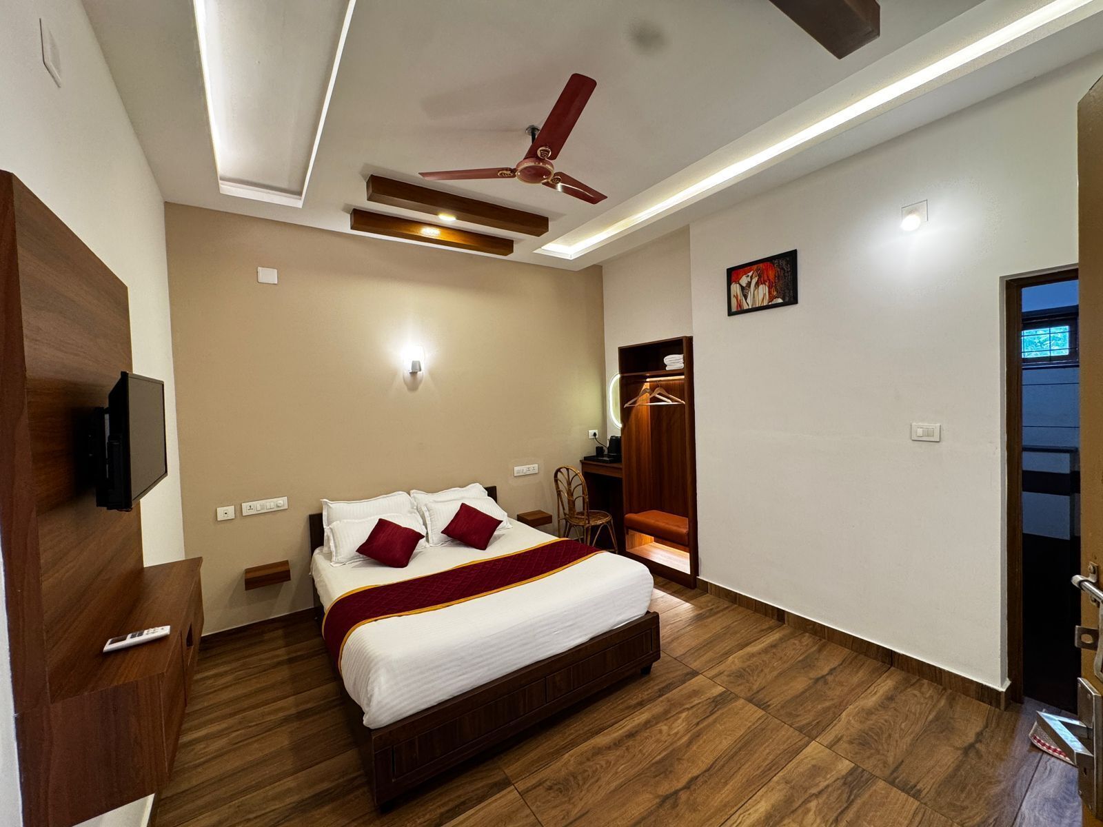 Une chambre d’hôtel équipée d’un lit, d’un ventilateur de plafond, d’une table de chevet, d’une télévision et d’une armoire.