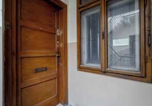 A wooden door with a metal handle and a window with a metal frame and a metal handle. - Old Town Cream Apartment (Kraków)
