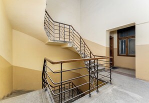 A spiral staircase with metal railings and a wooden handrail, leading to an upper floor. - Old Town Cream Apartment (Kraków)