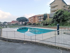 Ein rechteckiger Swimmingpool mit Metallzaun, umgeben von einem befestigten Bereich.