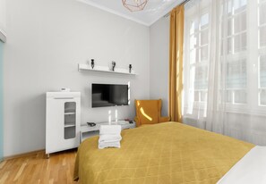Ein Hotelzimmer mit einem Bett, einem Fernseher, einem Kleiderschrank und einem Fenster mit Vorhängen.