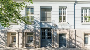 A building with a central entrance, multiple windows, and a door with a sign above it. - Topolowa Comfort Apartment (Kraków)