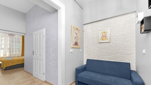 A modern interior with a blue sofa, a door, and a wall with a geometric pattern. - Topolowa Comfort Apartment (Kraków)