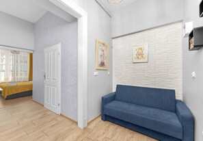 Ein modernes Interieur mit einem blauen Sofa, einer Tür und einer Wand mit geometrischem Muster.