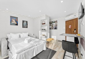 A modern hotel room with a bed, a desk, a chair, and a wall with framed pictures. - Podgórze Boutique Studio (Kraków)