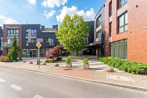 Un immeuble moderne avec une enseigne indiquant « May Apartments » et un passage piéton.