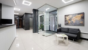 A modern office space with a reception area, a glass partition, a sofa, and a world map on the wall. - Podgórze Boutique Studio (Kraków)