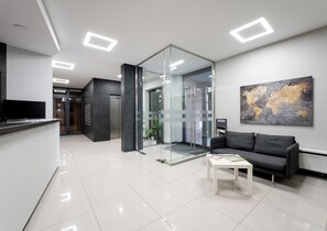 A modern office space with a reception area, a glass partition, a sofa, and a world map on the wall. - Podgórze Boutique Studio (Kraków)