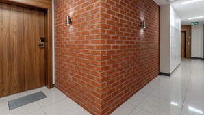 A hallway with a wooden door, a brick wall, and a tiled floor. - Podgórze Boutique Studio (Kraków)