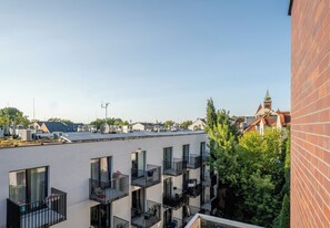 A modern building with multiple balconies, a clear sky, and a distant church spire. - Podgórze Boutique Studio (Kraków)