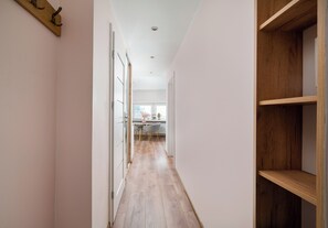 Un pasillo con suelo de madera que conduce a un comedor con una mesa y sillas.