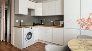 Cozinha compacta com máquina de lavar, micro-ondas e área de refeições com mesa.