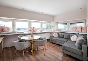 A modern living room with a round table, grey sofas, and a view of the city through large windows. - Zgoda 13 Modern City Apartment (Warszawa)