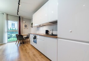 Une cuisine moderne avec des meubles blancs, un plan de travail en bois et une vue sur un balcon.
