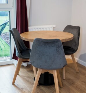 Une table ronde en bois, accompagnée de quatre chaises grises à revêtement rembourré.