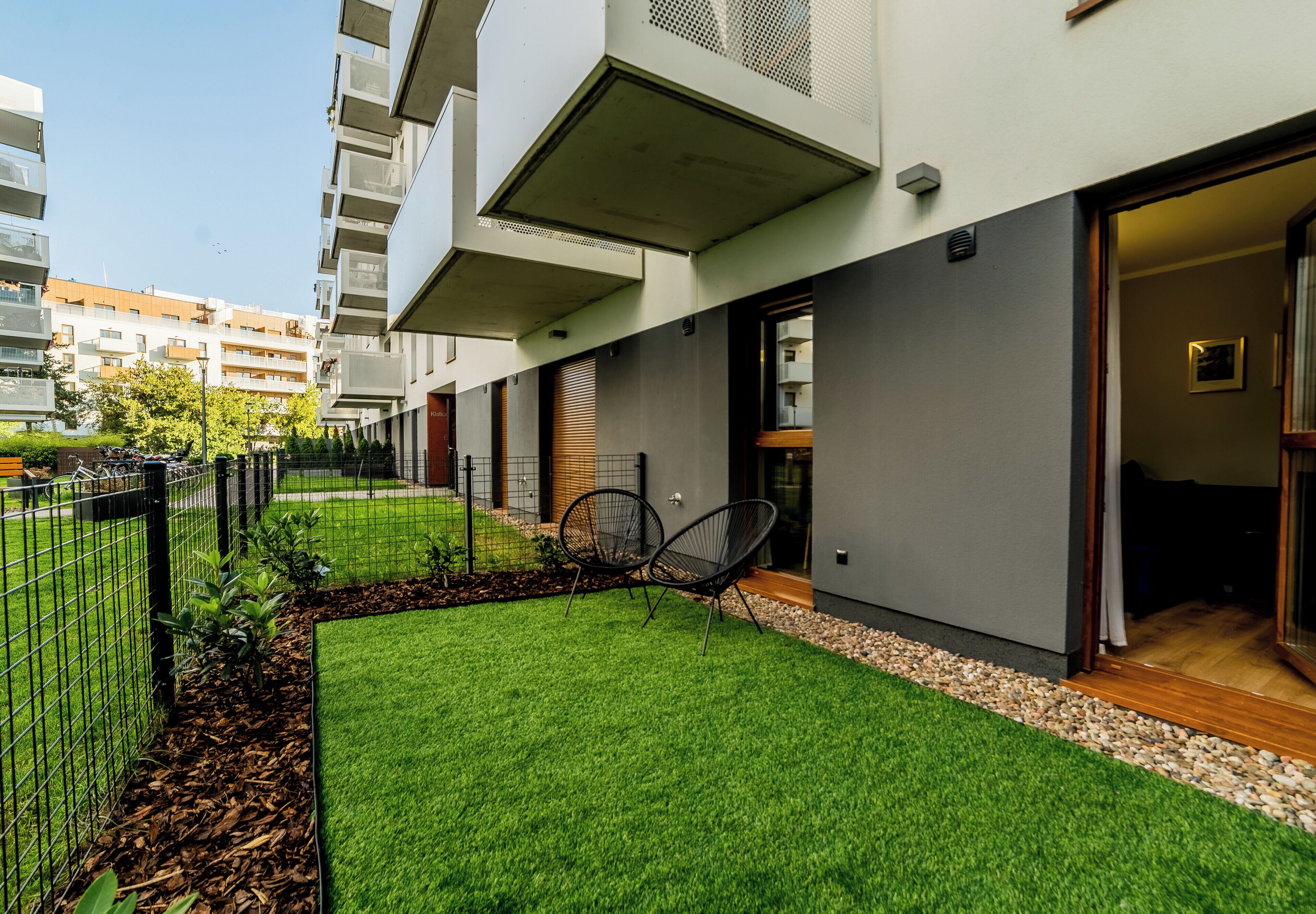 A modern building with a flat roof, a balcony, and a door leading to a covered outdoor area.