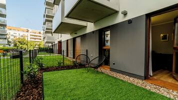 A modern building with a flat roof, a balcony, and a door leading to a covered outdoor area.