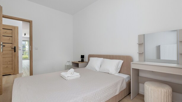 A modern bedroom with a bed, a desk, and a mirror. - Zielonego Mostu Cozy Elegant Apartment (Szczecin)