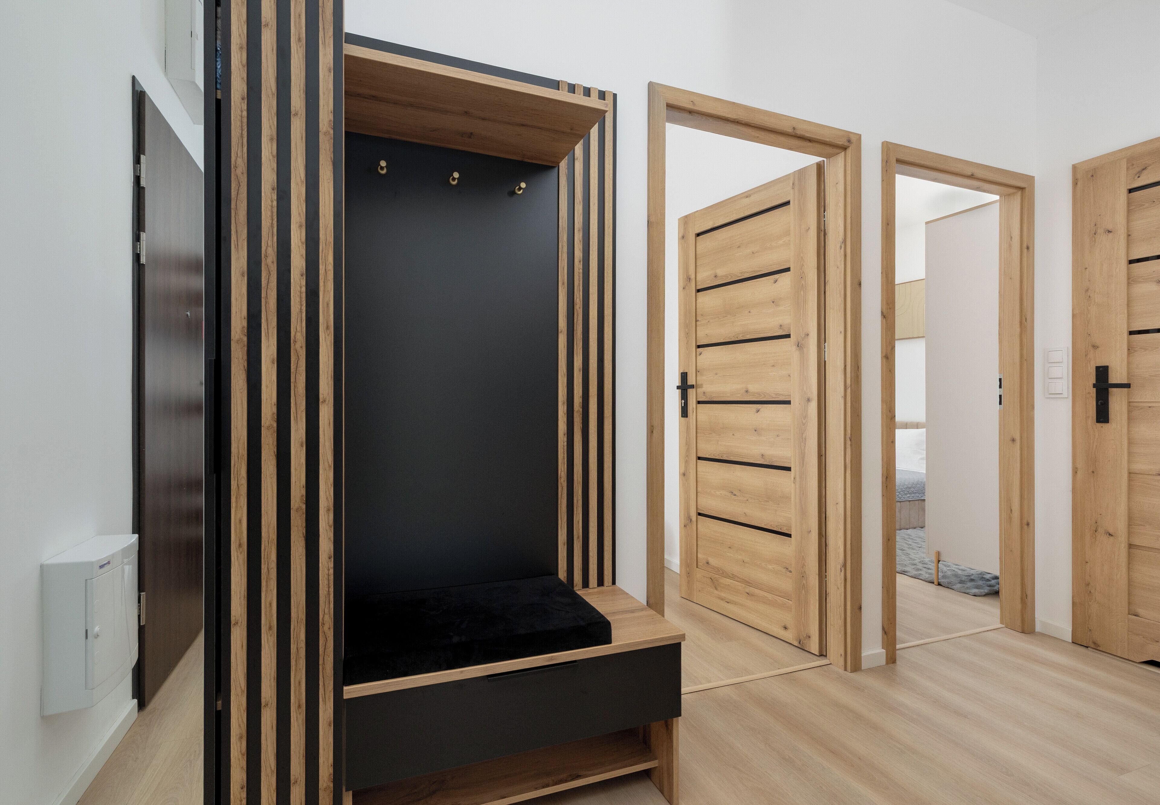 Ein Zimmer mit integriertem Kleiderschrank, einer schwarzen Bank und Holztüren.