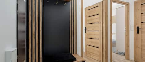 Ein Zimmer mit integriertem Kleiderschrank, einer schwarzen Bank und Holztüren.