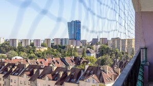 Un paisaje urbano con un edificio moderno y alto destacándose al fondo, rodeado de edificios residenciales con techos inclinados.