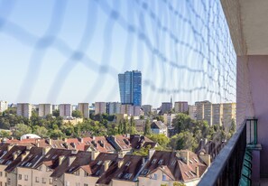 Eine Stadtsicht mit einem markanten, modernen Hochhaus im Hintergrund, umgeben von Wohngebäuden mit Satteldächern.