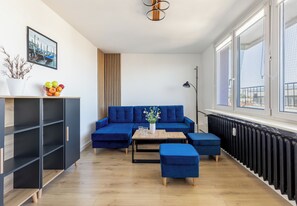 Ein modernes Wohnzimmer mit einem blauen Sofa, einem kleinen Tisch und einem Blumentopf.