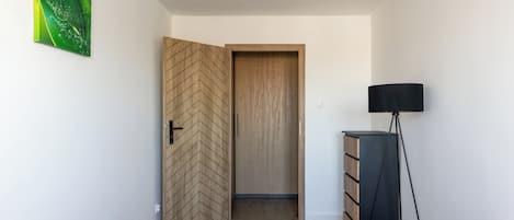 A bedroom with two wooden beds, a wooden wardrobe, a floor lamp, and a green abstract painting on the wall.