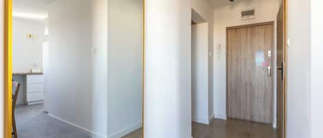 A hallway with a wooden door, a light switch, and a wall-mounted light fixture.