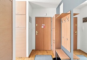 Un pasillo con taquillas de madera, una puerta con un letrero y un banco.