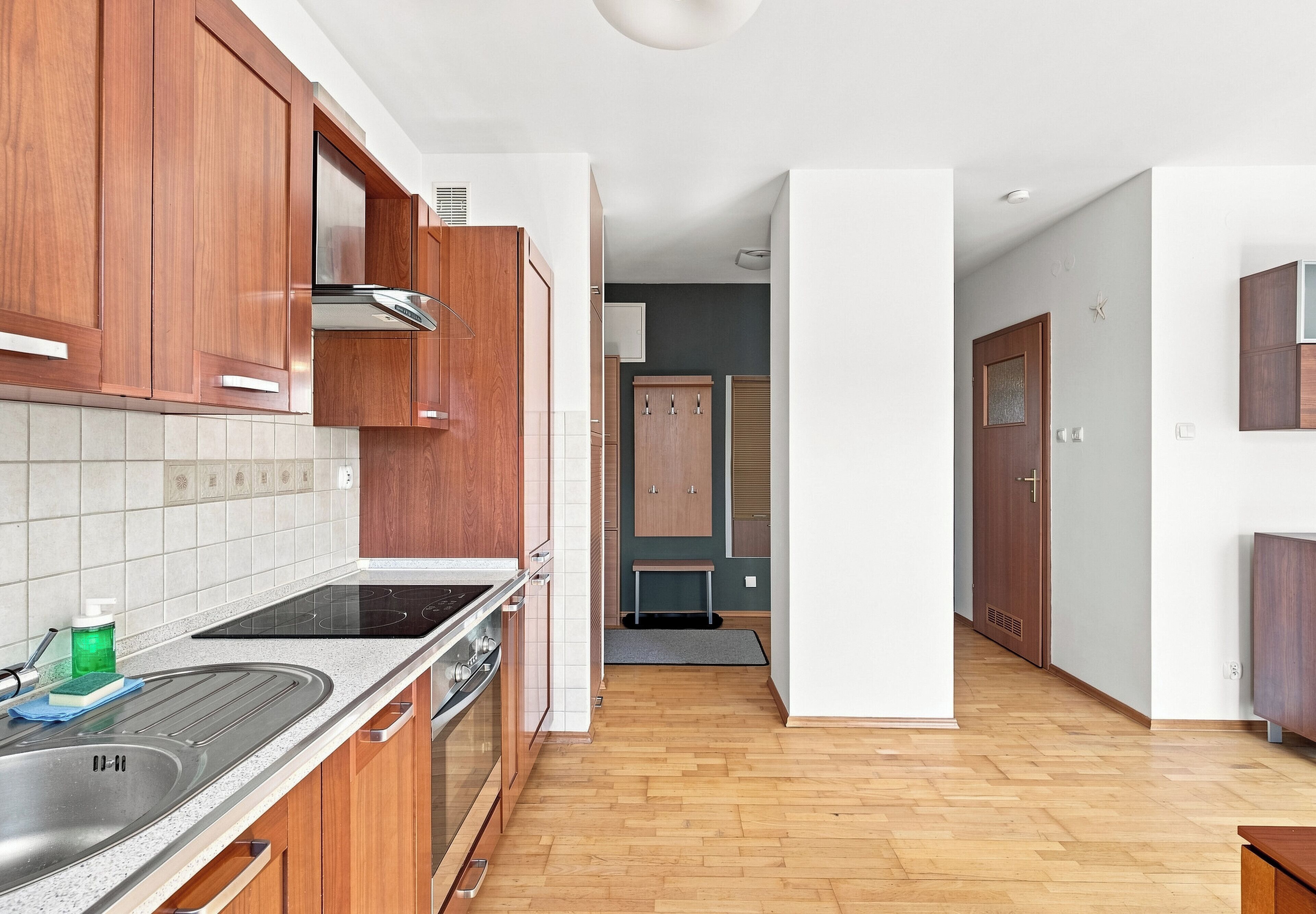 Una cocina moderna con armarios de madera, un lavamanos de acero inoxidable y una estufa negra.