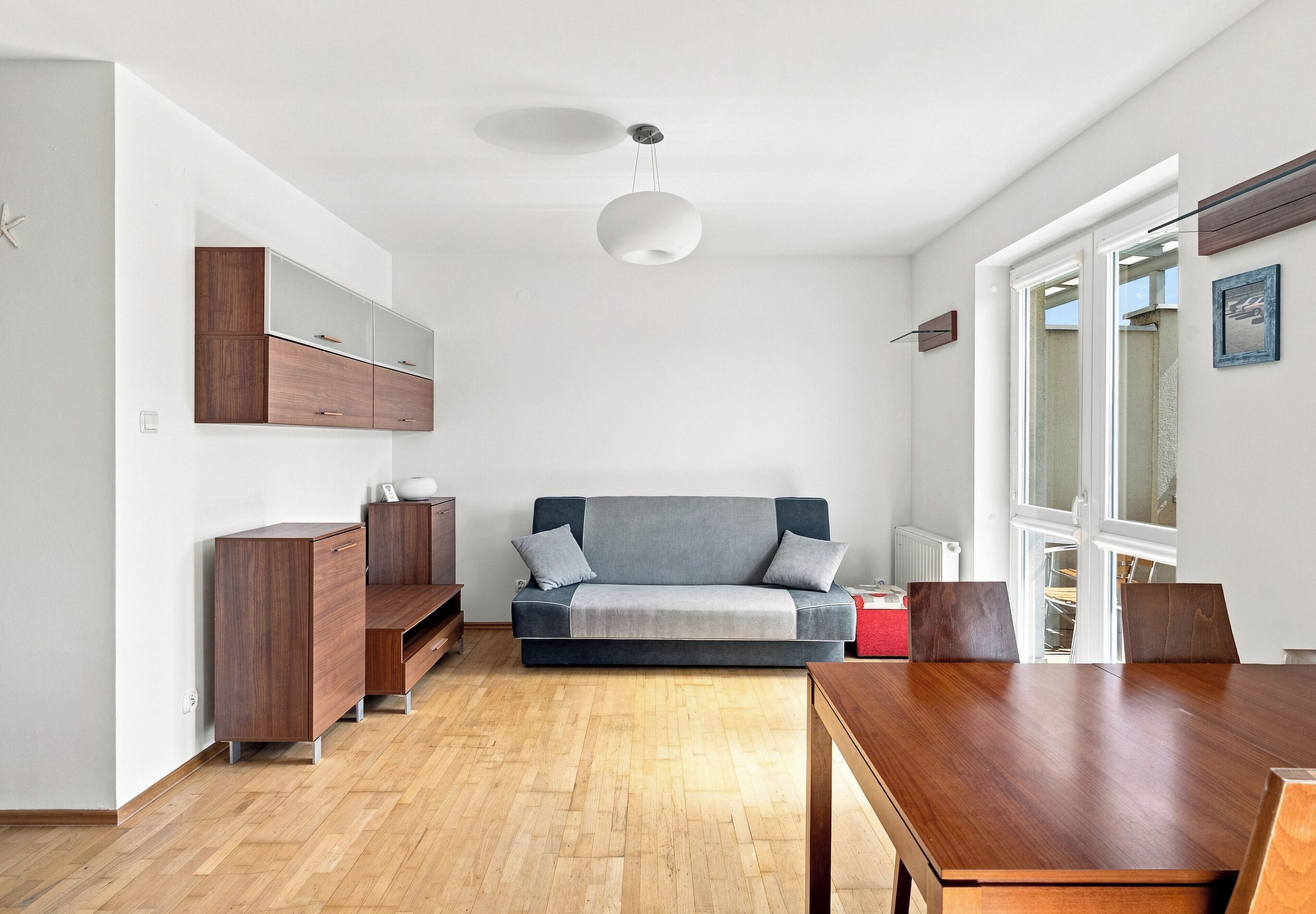 A modern living space with a sofa, wooden furniture, and a dining area.
