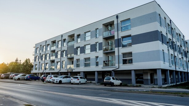 Um edifício residencial com vários andares e uma área de estacionamento na frente.