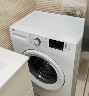 A front view of a white washing machine with a digital display and control panel. - Luboń City Comfort Studio (Luboń)