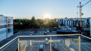 Um estacionamento com vários carros, uma grua de construção e edifícios ao fundo.