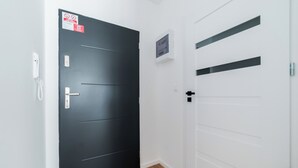 Um corredor com uma porta cinza escura à esquerda e uma porta branca à direita.