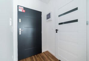 Ein Korridor mit einer dunkelgrauen Tür links und einer weißen Tür rechts.