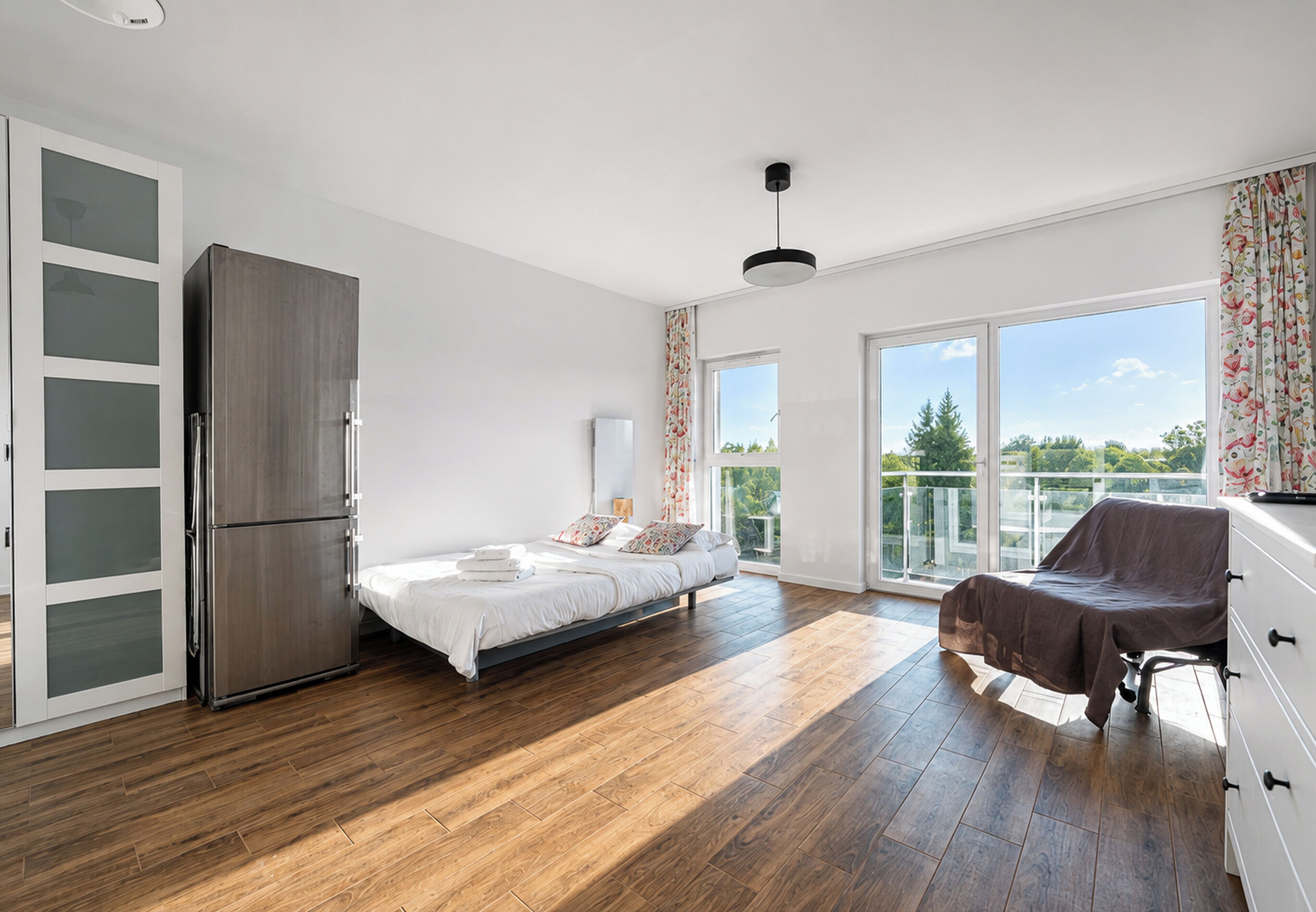 Une chambre moderne avec un lit, une armoire, un balcon et une vue sur la verdure.