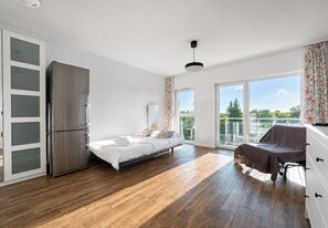 Une chambre moderne avec un lit, une armoire, un balcon et une vue sur la verdure.