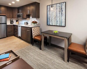 A modern kitchen with dark wood cabinets, stainless steel appliances, and a dining area with a table and chairs. - Steamboat Springs | Mountain Ski | Ski Access & Hot Tub (Steamboat Springs)